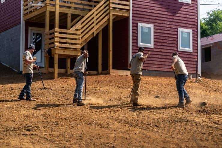 Workers leveling ground at construction site.